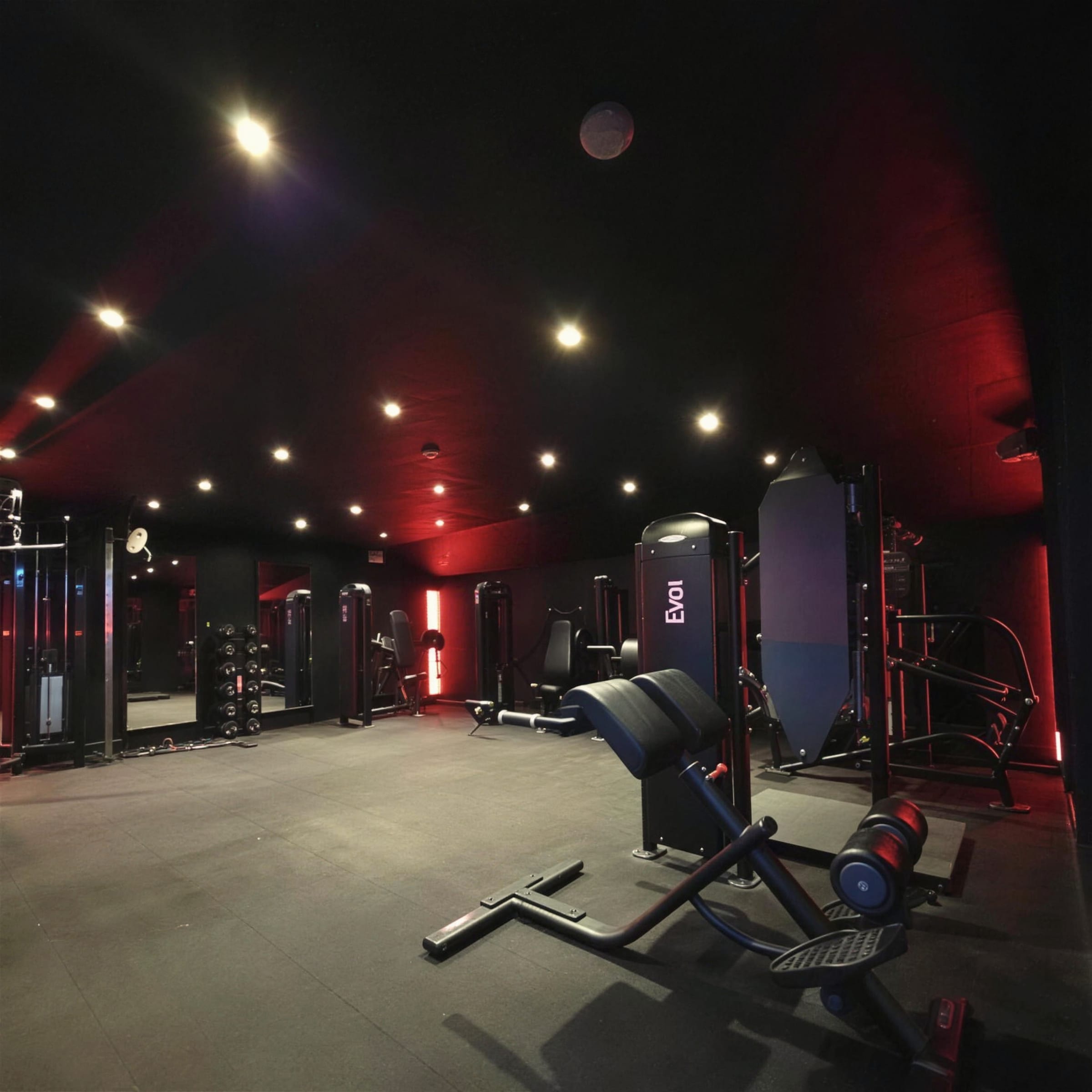 Machine zone under warm downlights with red LED wash grazing the black ceiling and walls.