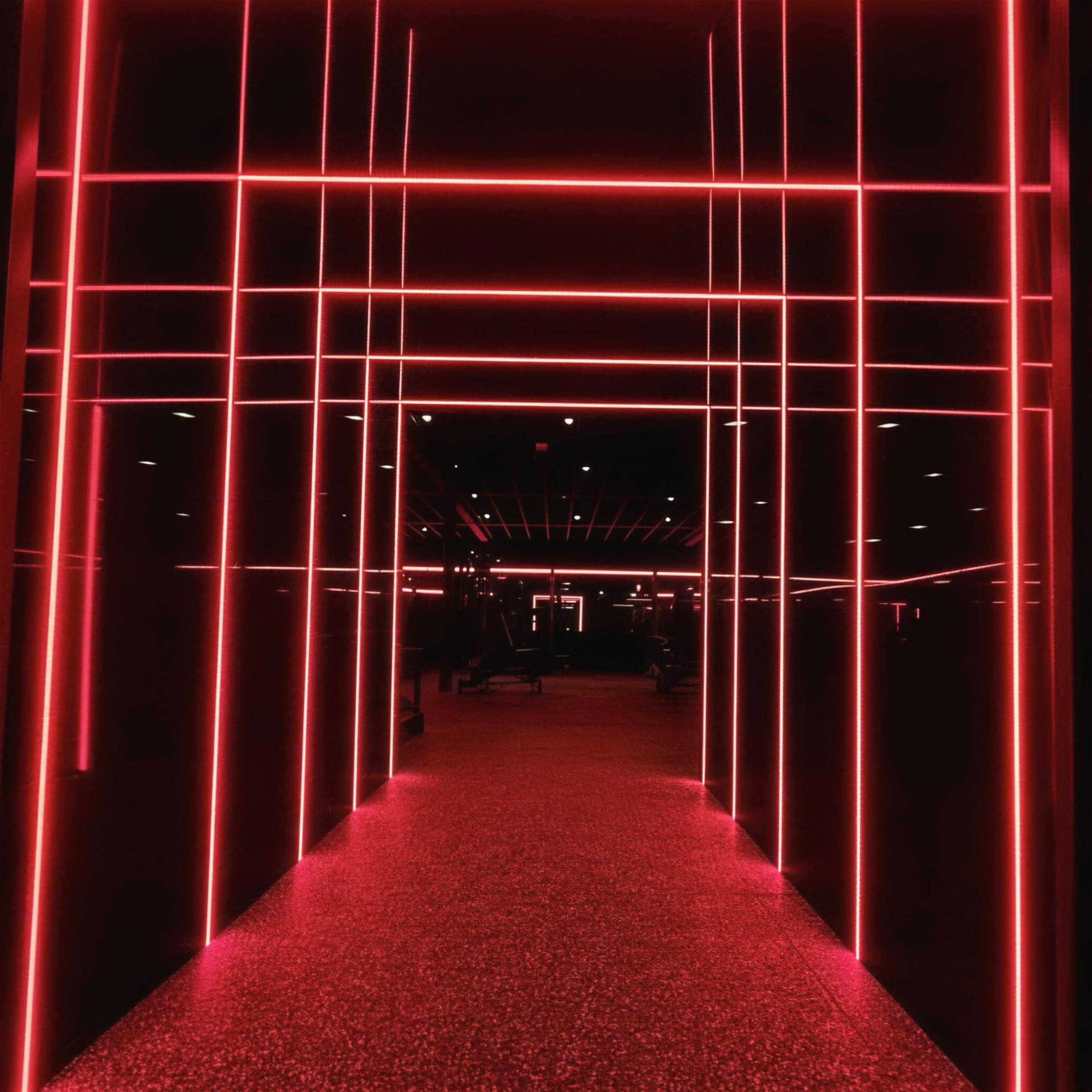 Deep symmetrical red neon-grid corridor, LED lines wrapping walls and ceiling above a glittering red floor.