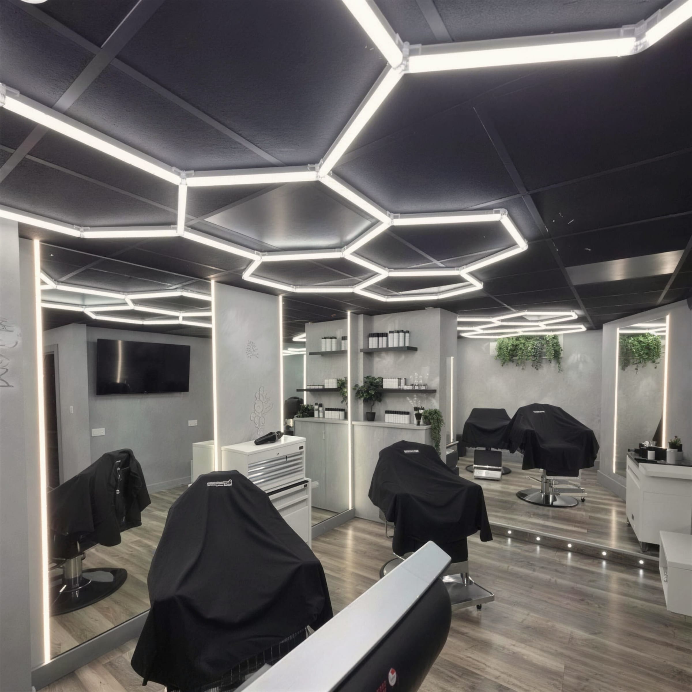 Finished barbershop interior with black hexagon LED ceiling frames, plaster walls, LED-edged mirrors and covered styling chairs.
