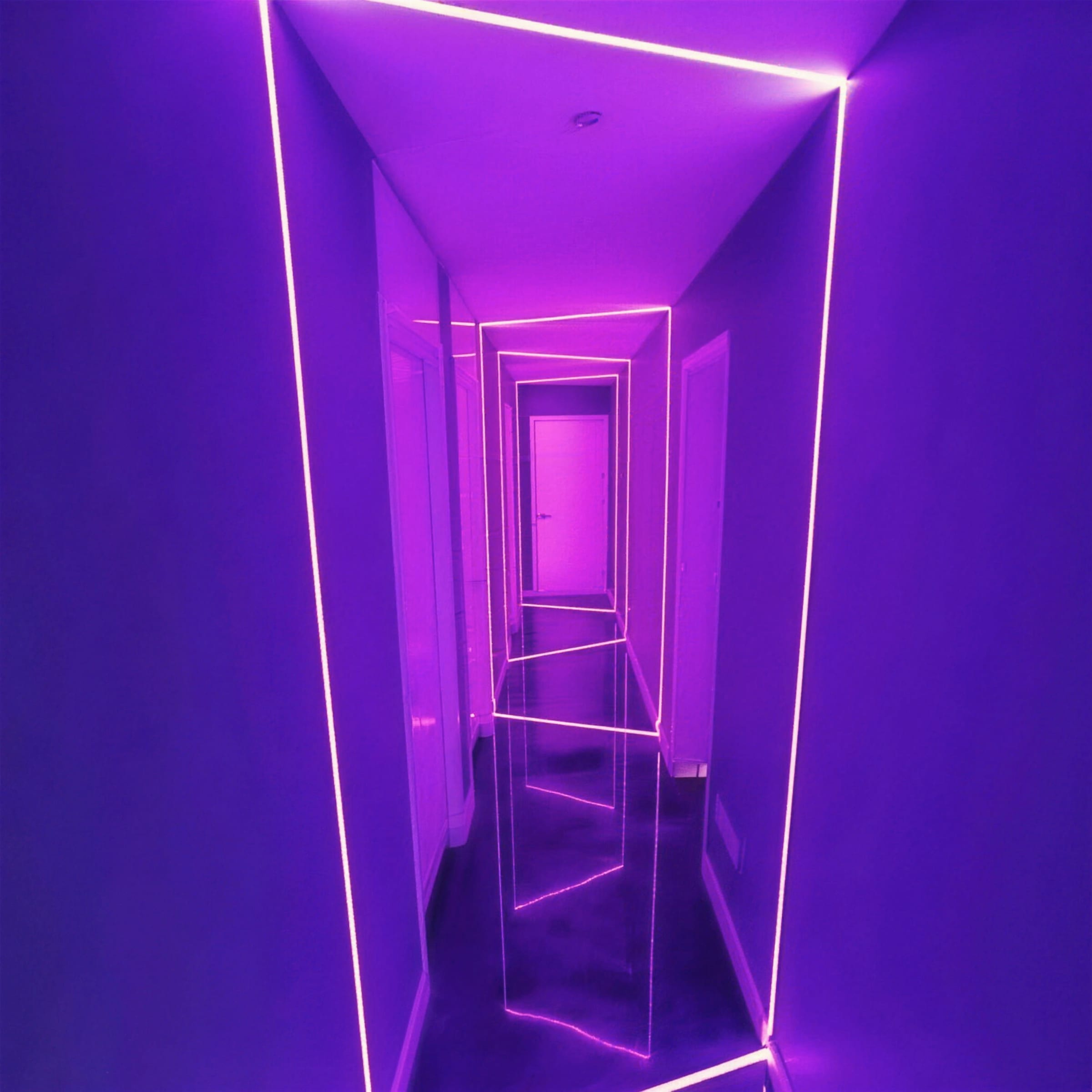 Residential hallway outlined in violet LED strips with mirrored reflections multiplying the glowing frames.