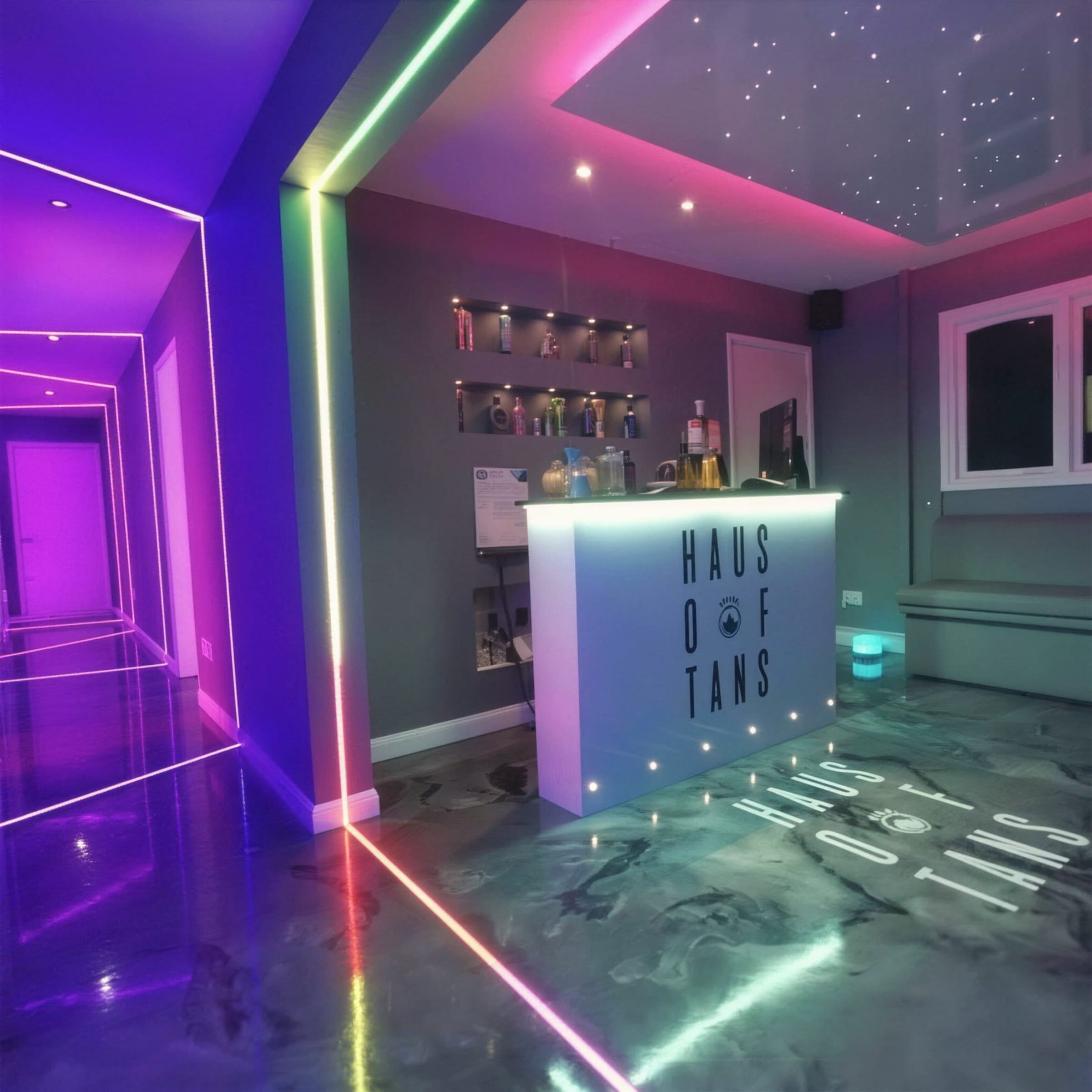 Commercial salon fit-out with multicolour neon LED strip framing, star-ceiling corner and a glossy metallic marble-effect floor with branded desk.