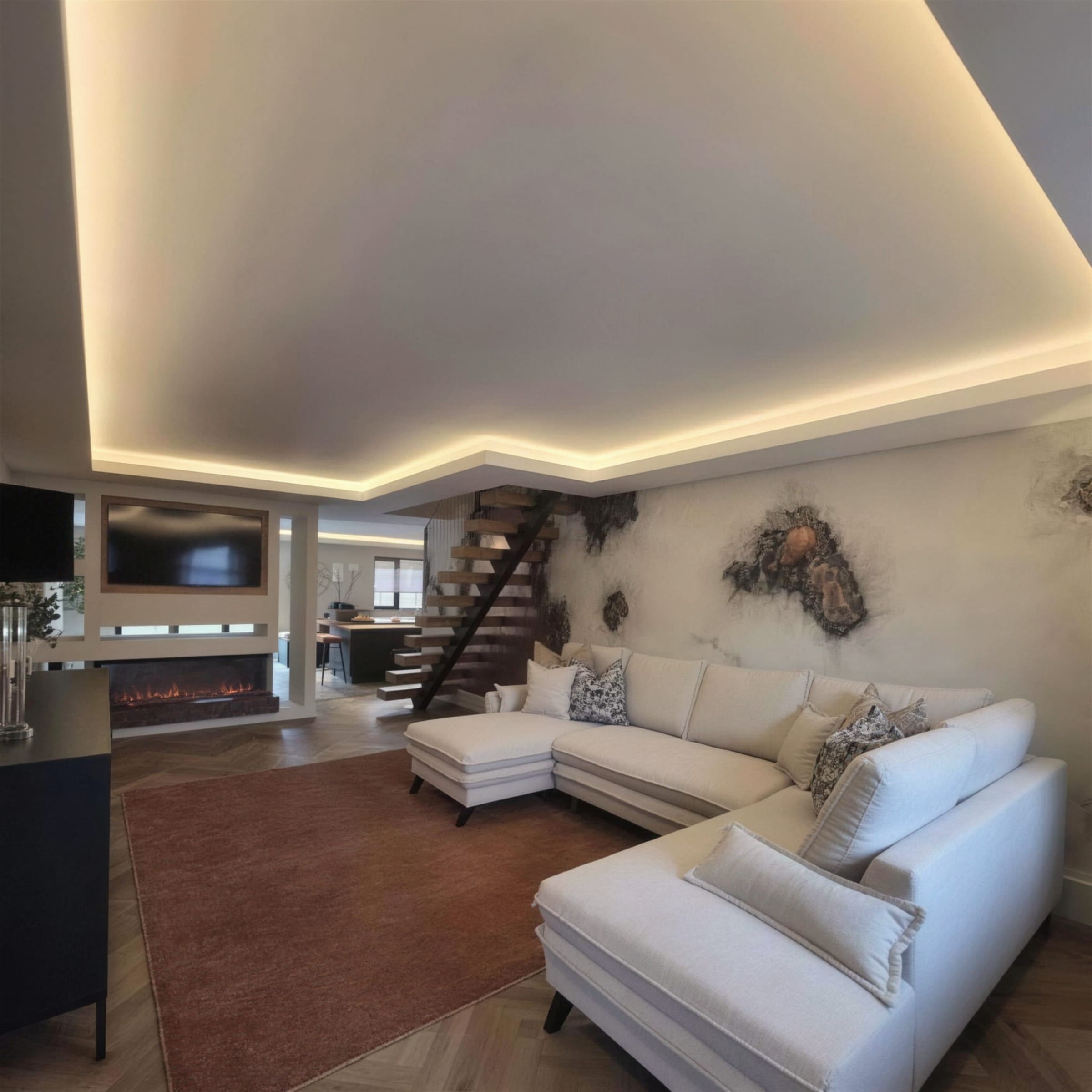 Elegant open living room wrapped in a warm LED cove-lit stepped ceiling, cream sofas, media fireplace and a copper-and-plaster art wall behind the staircase.