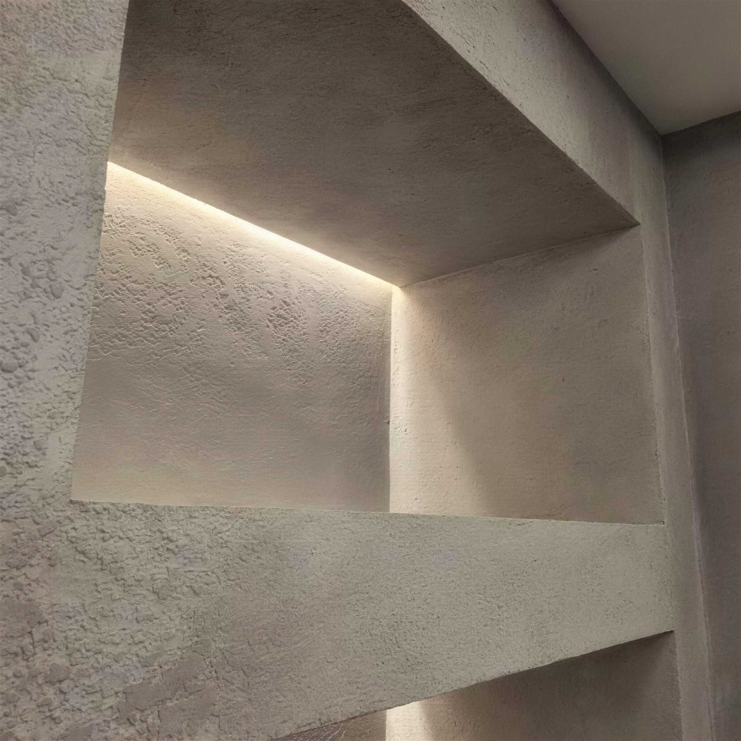 Sculptural wall niches in rough sand-toned plaster, each washed from within by a concealed warm LED strip.