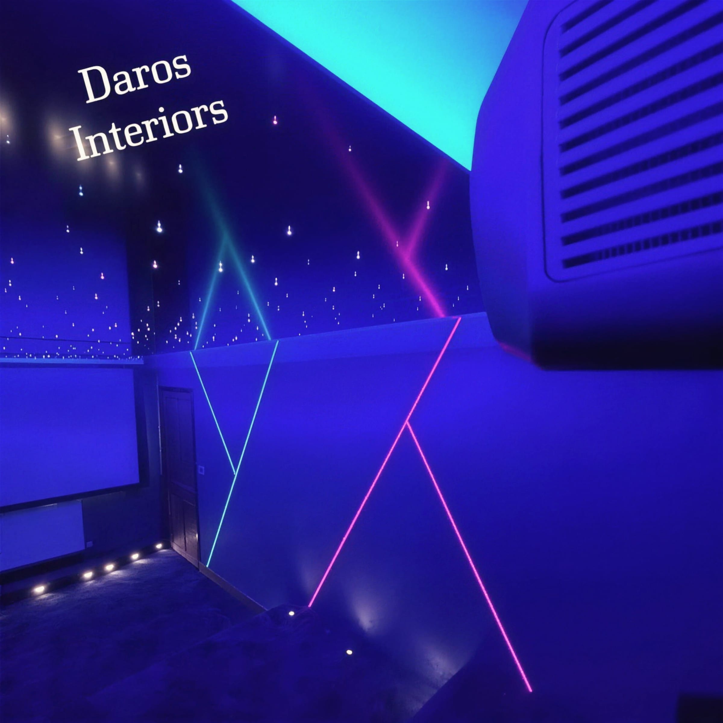 Blue-lit cinema room with fibre-optic star pinpoints across the ceiling and pink and teal neon lines crossing the wall, overlaid with a Daros Interiors watermark.