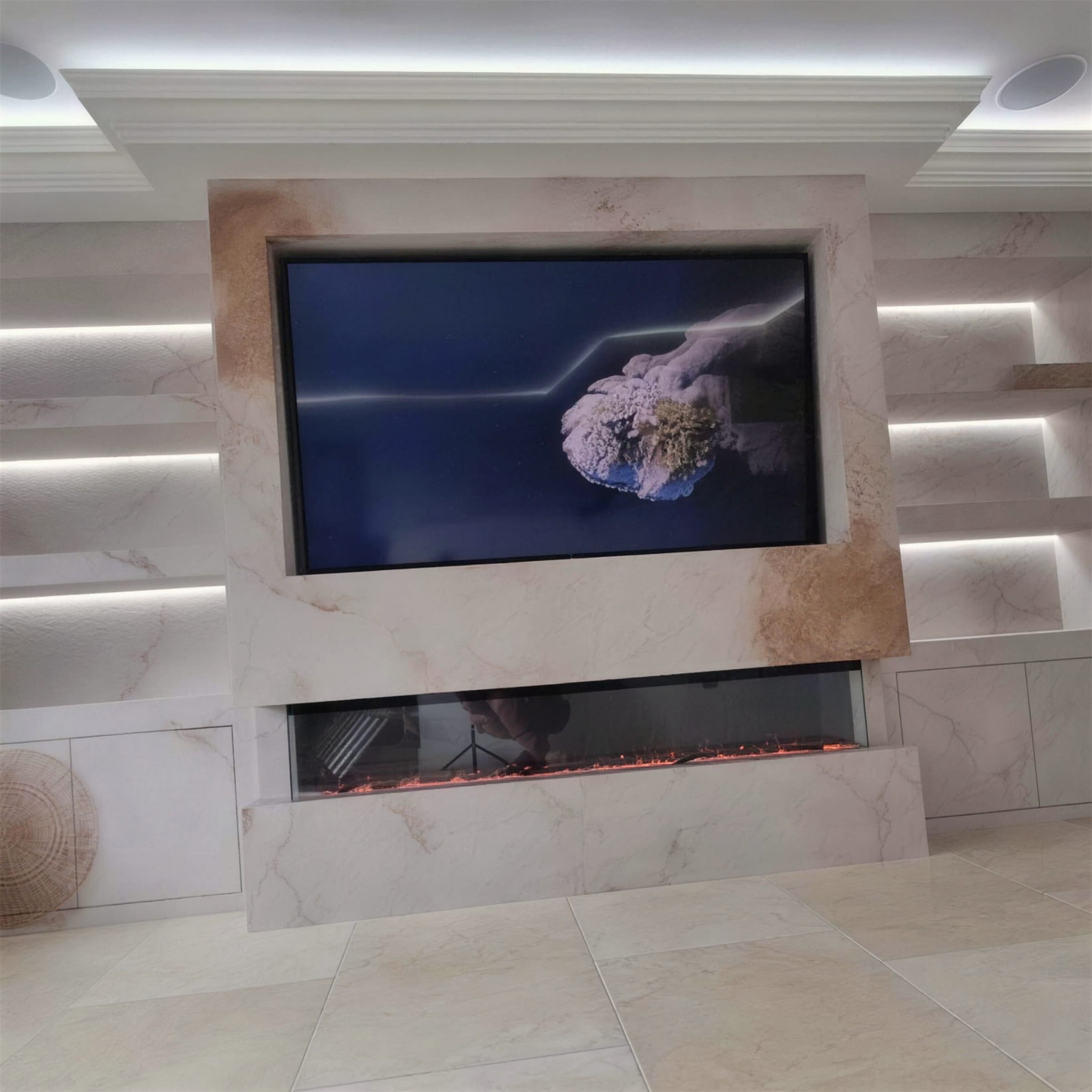 Veined marble-effect plaster media wall with flame-lit linear fire, cornice LED cove and washed wall panels.