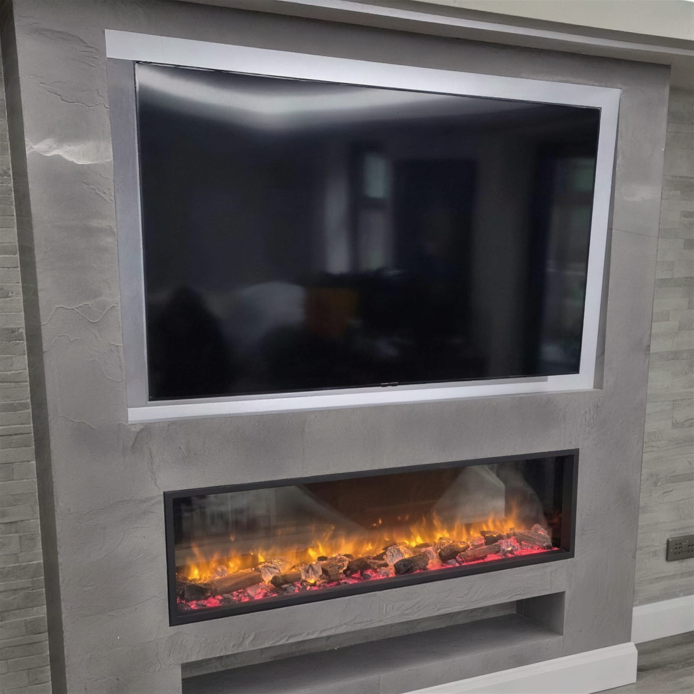 Grey slate and marble-effect media wall with split-face stone flanks, recessed TV and wide electric fire.