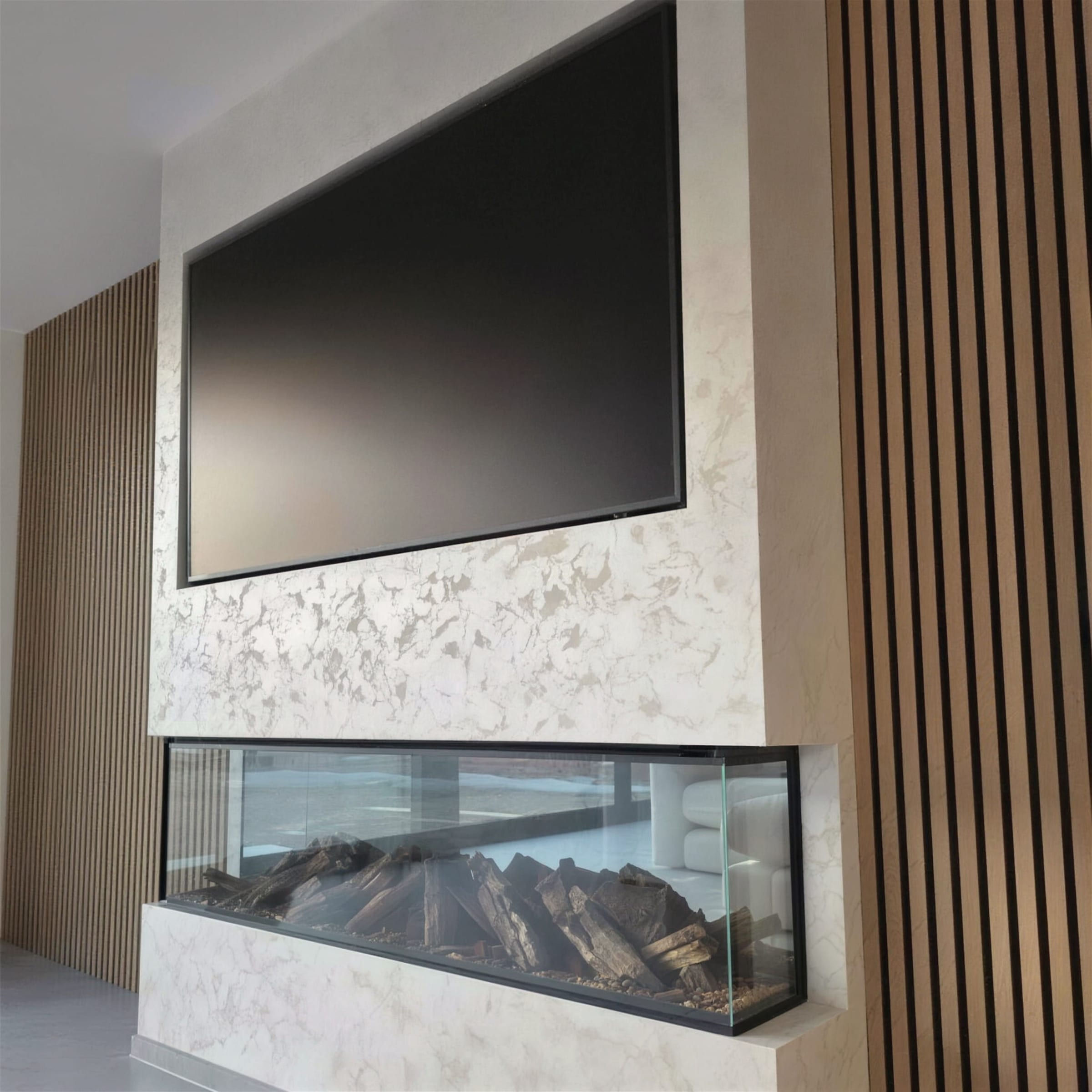 Luminous pearl marble-effect plaster media wall framed by oak slat panels, with recessed TV and a panoramic log-set fireplace; sharp daylight frame.