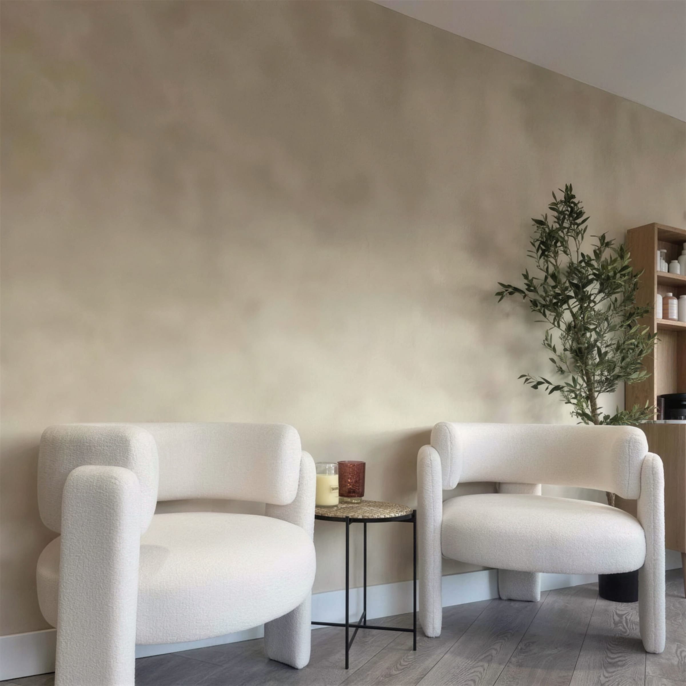 Two sculptural white boucle armchairs and a side table with candles against a softly clouded limewash plaster wall, olive tree at right.