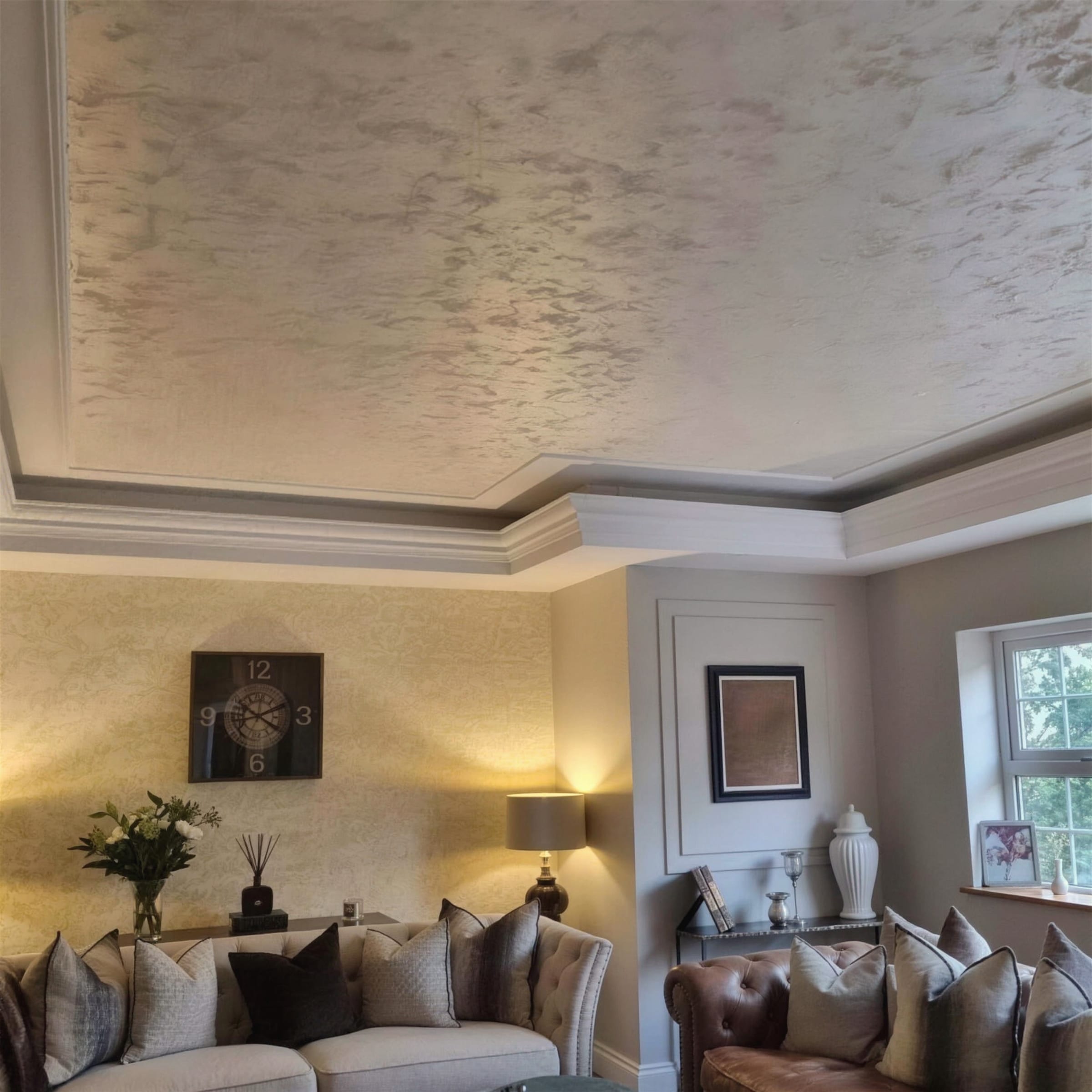 Furnished living room with a pearlescent metallic plaster ceiling set in a recessed tray, paired with gold textured plaster wall panels.